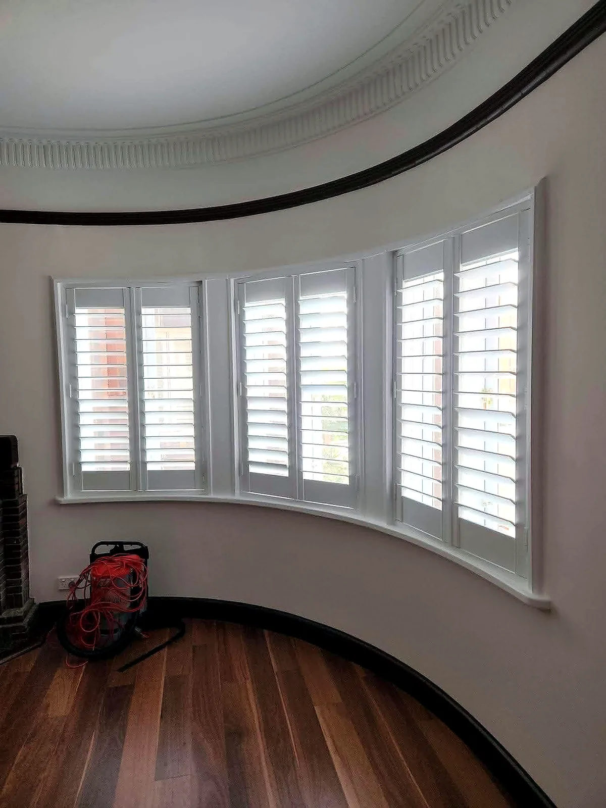 Curved bay window fitted with white plantation shutters in Brisbane