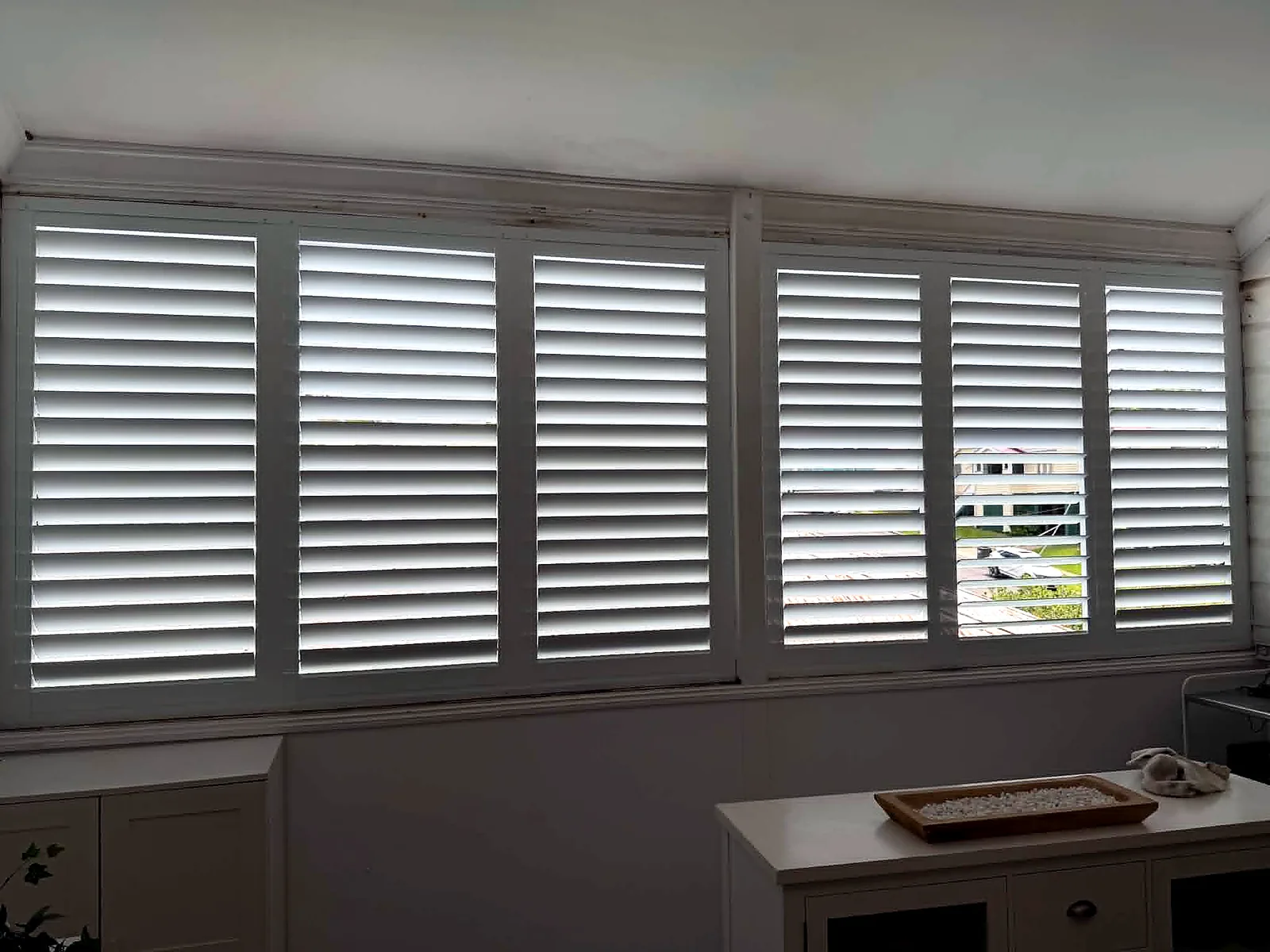 Wide window fitted with white plantation shutters in a Brisbane home